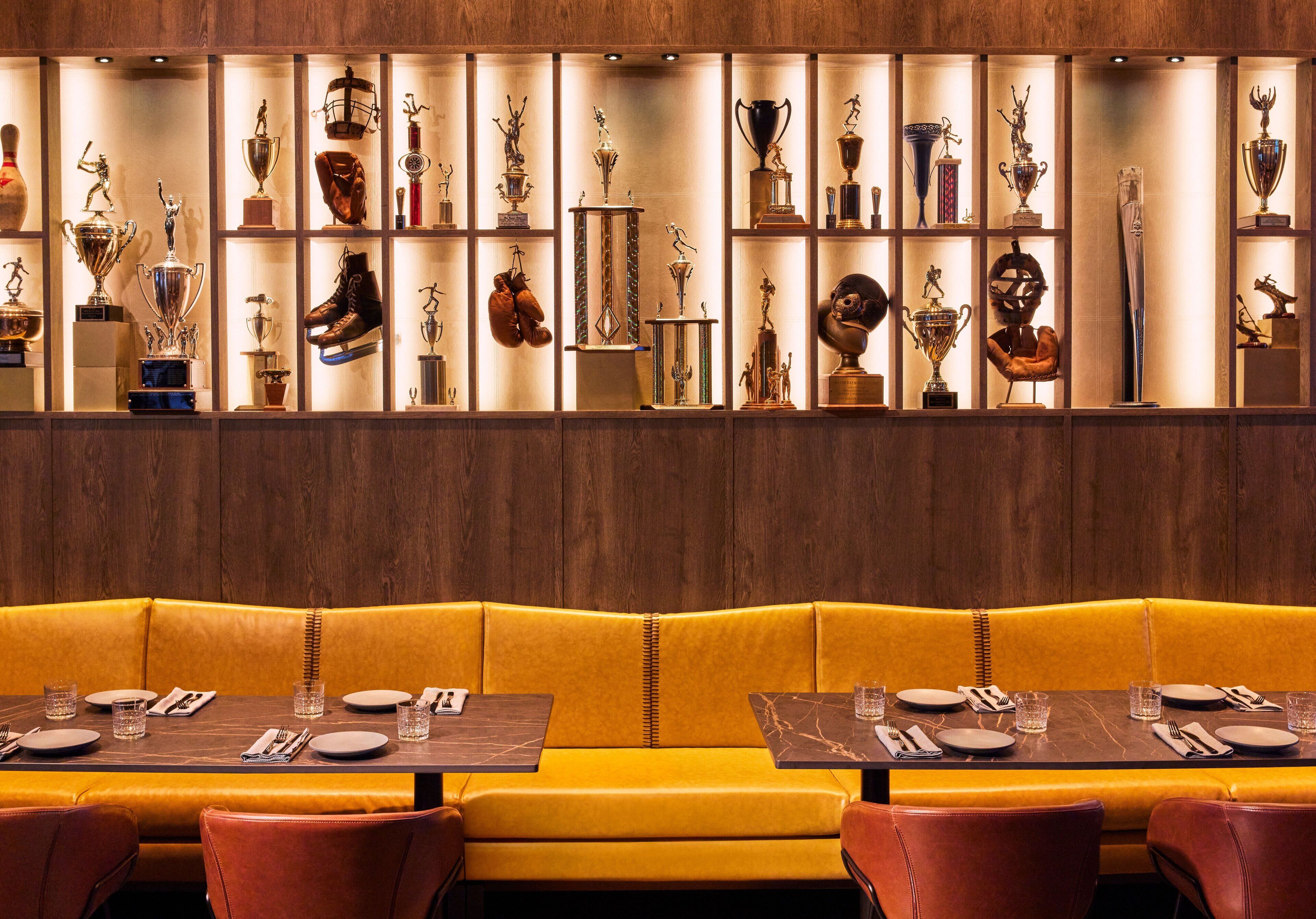 A restaurant with a yellow booth seating area and a wall of trophies.