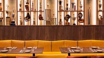 A restaurant with a yellow booth seating area and a wall of trophies.
