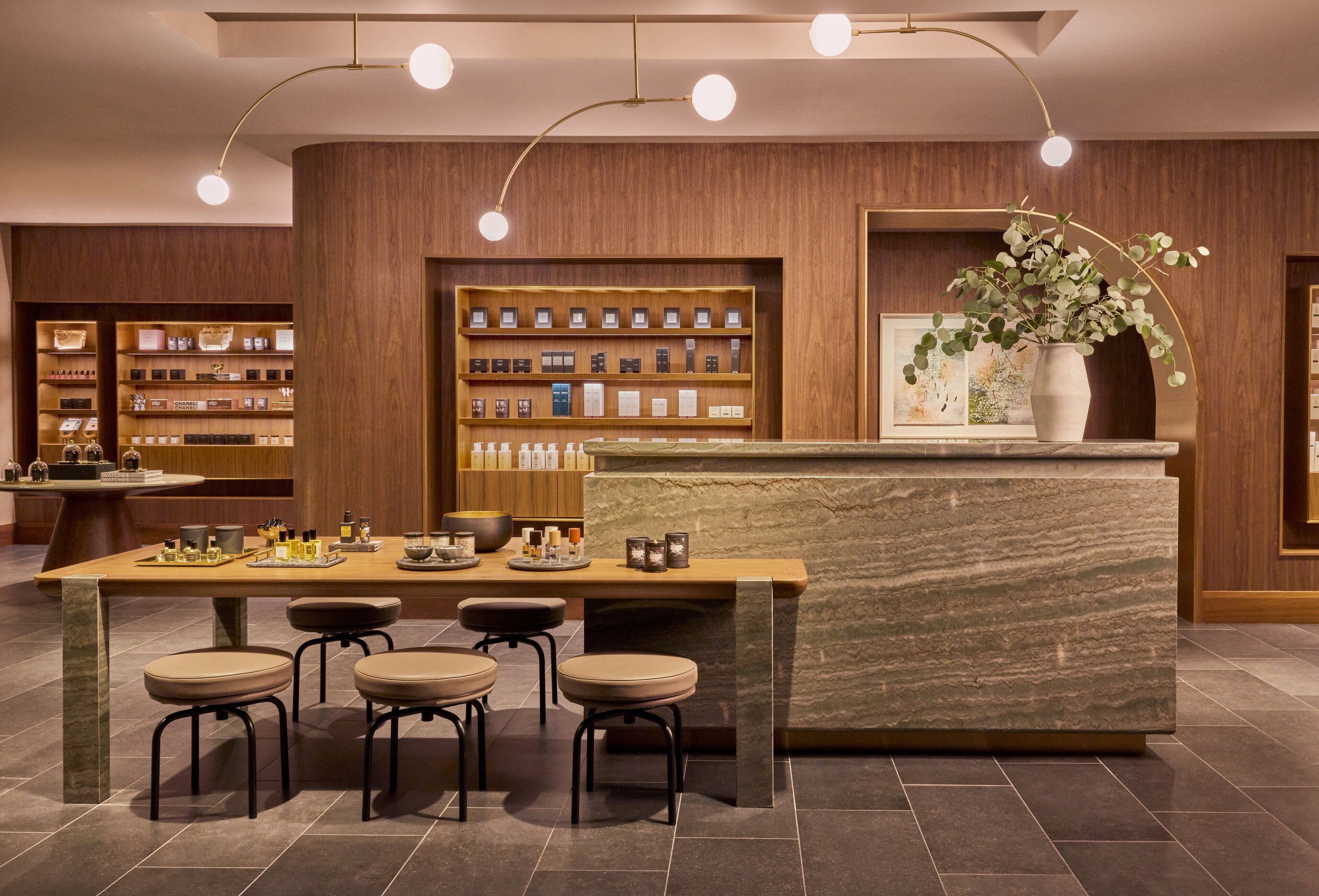Un área de bar moderna con una barra de mármol, estantes de madera con botellas y una planta en maceta.