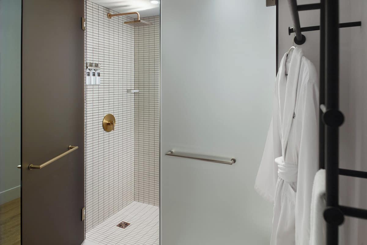 A bathroom with a shower, a towel rack, and a door.