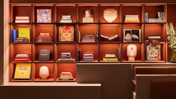 A well-organized bookshelf with various books and decorative items, including a bust and a vase with flowers.