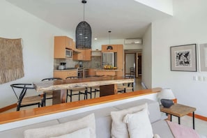 Een moderne keuken met houten kasten, een centraal eiland en hangende lampen.