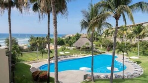 Un resort con una amplia piscina rodeada de palmeras y vistas al océano.