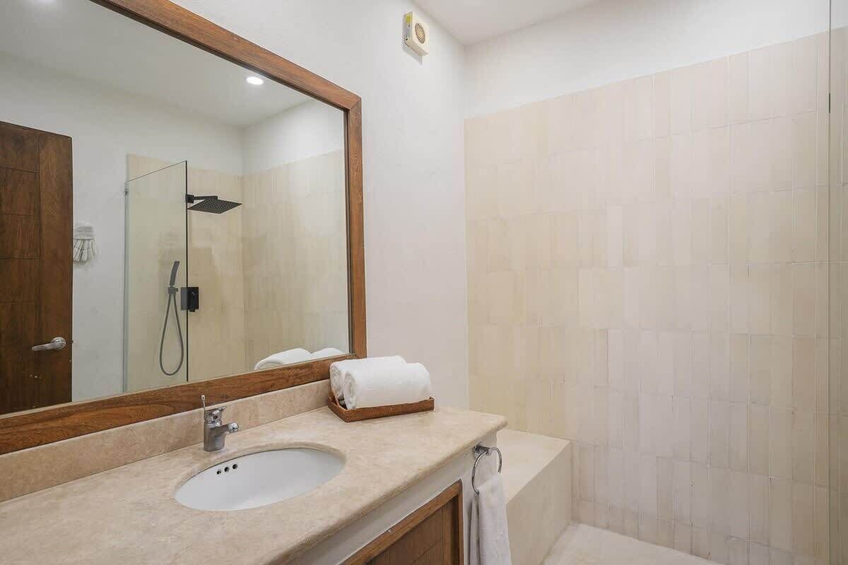 A modern bathroom with a large mirror, a sink, and a shower.