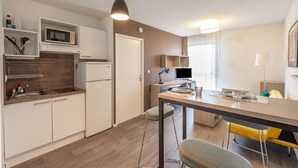 A modern kitchen with a microwave, refrigerator, and dining area with stools. - Auriol - Appt contemporain (Toulouse)