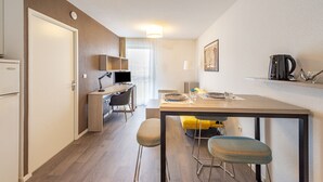A modern kitchen with a dining area, a refrigerator, a coffee maker, and a television. - Auriol - Appt contemporain (Toulouse)