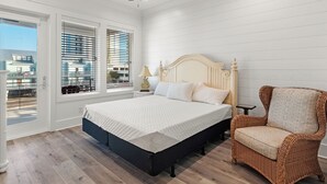 A bedroom with a bed, a chair, a nightstand, a ceiling fan, and large windows with blinds. - 😎 Night Heron, West. ⭐️⭐️⭐️⭐️⭐️ 6BR. Heated Pool. Beachview. Gorgeous! (Gulf Shores)