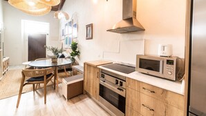 Una cocina moderna con armarios de madera, horno empotrado, microondas y un comedor con una mesa redonda y sillas.