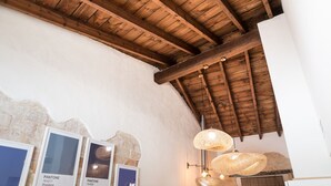 Un interior rústico con vigas de madera a la vista, un techo alto y lámparas de fibra.