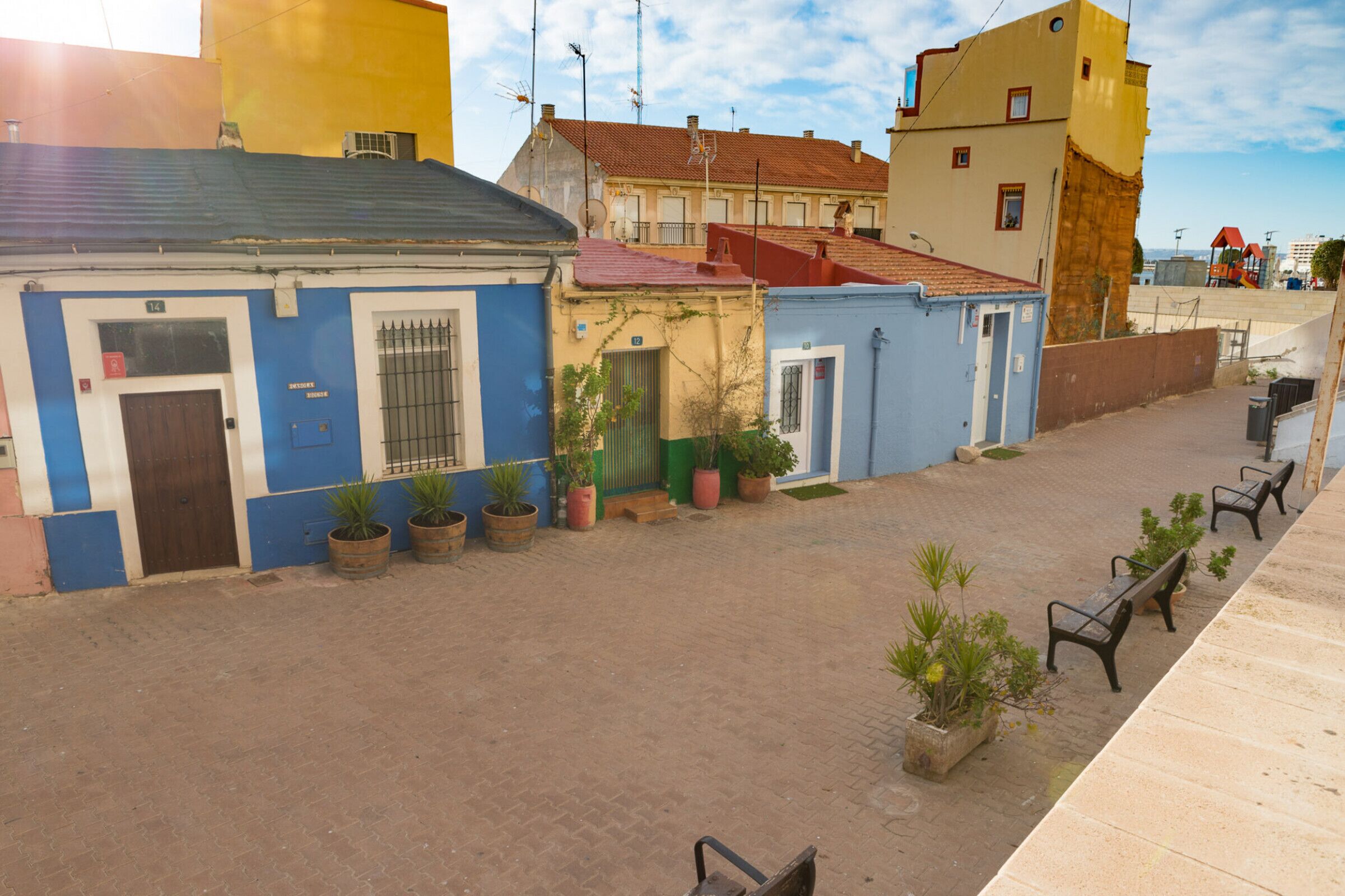 A narrow street with buildings on both sides, featuring a mix of residential and commercial properties.