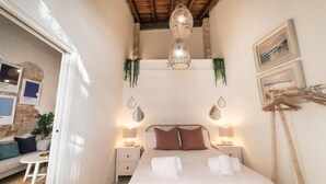 Un dormitorio con una cama grande, lámparas de noche, una lámpara colgante y cuadros en la pared.