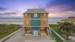 Un edificio a due piani con un balcone, un garage e vista sulla spiaggia.