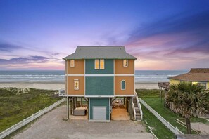 A two-story building with a balcony, a garage, and a view of the beach. - Beachfront Sleeps 14 | Hot Tub | Fire Pit and Deck (Galveston)