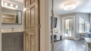 A modern bathroom with a large mirror, vanity, and a wooden door.