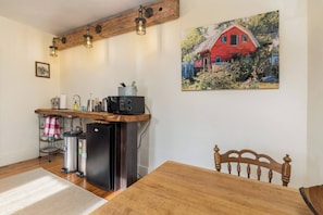 Una cocina con mostrador de madera, un refrigerador, un lavamanos y una mesa de comedor con una silla.