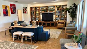 A living room with a TV, sofas, a coffee table, and a bookshelf.