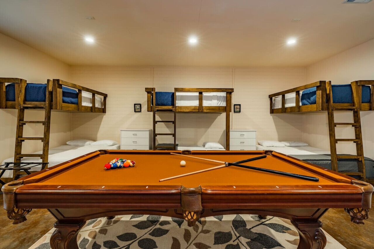 A pool table in a room with bunk beds and a ladder.