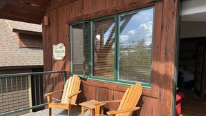 A wooden deck with two wooden chairs and a small table.