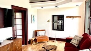 A living room with a TV, wooden furniture, a red sofa, and a wooden coffee table.