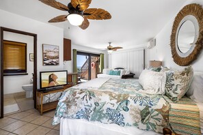 A bedroom with a bed, a television, a ceiling fan, and a large mirror. - Kona's Shangri La: Private Oceanfront Home w/ Pool, Spa & Elevator (Kailua Kona)