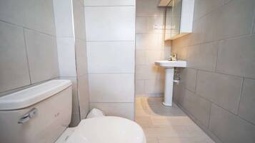 Een bad/douchecombinatie, handdoeken, toiletpapier