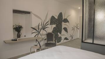 Una habitación de hotel moderna con una cama, una silla, una mesita y un mural en la pared.