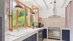 Une cuisine moderne dotée d’une grande fenêtre, d’un four encastré et de meubles de rangement aux couleurs sombres.