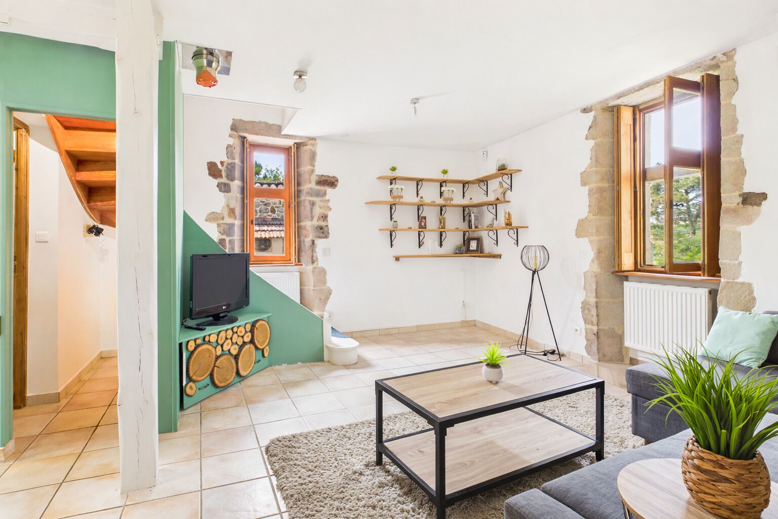 A living room with a TV, coffee table, and shelves with decorative items.