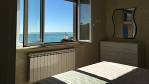 A bedroom with a bed, a dresser, and a window with a view of the sea. - Home Away From Home (Monterosso al Mare)