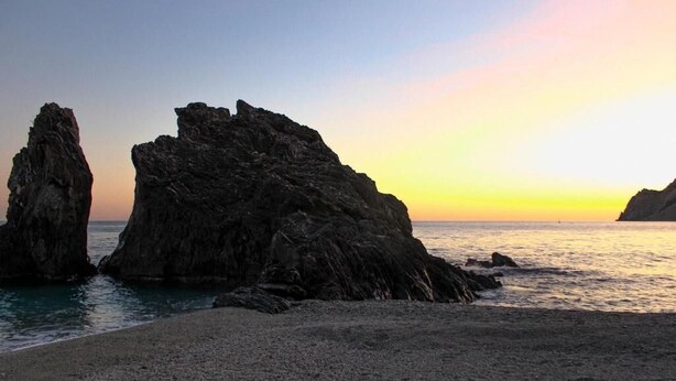 A coastal landscape with prominent rock formations and a beach. - Home Away From Home (Monterosso al Mare)