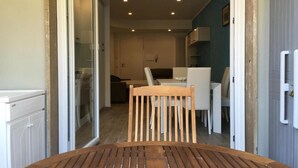 A wooden table and a chair in a room with a glass door leading to a kitchen area. - Home Away From Home (Monterosso al Mare)