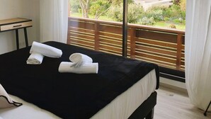 A hotel room with a bed, a small table, and a view of the outdoors. - Villa Maria 2. 12 pers, piscine chauffée, 5 min plage (sainte lucie de porto vecchio)