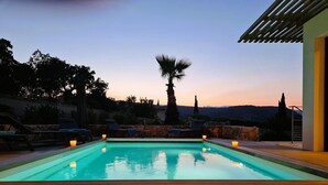 A swimming pool with lounge chairs and candles, surrounded by stone walls and trees, with a view of hills in the background. - Villa Maria 2. 12 pers, piscine chauffée, 5 min plage (sainte lucie de porto vecchio)