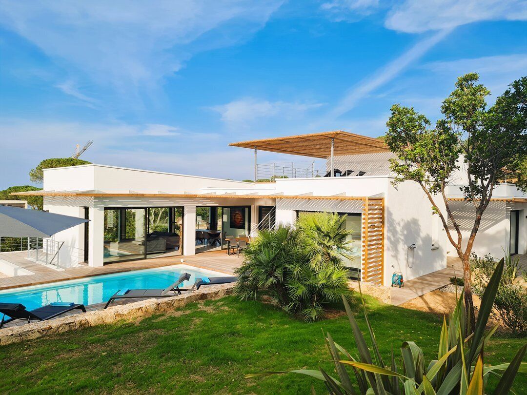 Una casa moderna con piscina, ampie finestre e un'area esterna coperta.