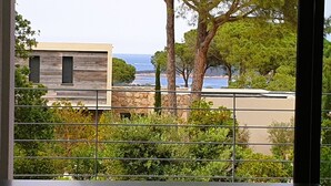 A modern building with a view of the sea through a metal fence. - Villa Maria 2. 12 pers, piscine chauffée, 5 min plage (sainte lucie de porto vecchio)