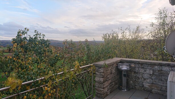 Un balcon avec un mur en pierre, une rambarde en métal et une antenne parabolique.