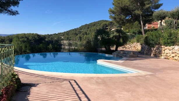A clear blue swimming pool with a stone wall and a paved deck. - St Raphaël/App 4 pers/superb sea view/pool/wifi/climate (Saint-Raphaël)