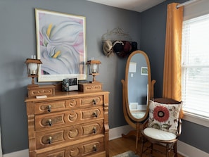 Relax in a stylish room with a dresser, abstract art, and a comfortable chair.