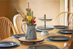 Enjoy a beautifully set dining experience with a rustic pitcher centerpiece and comfortable seating.