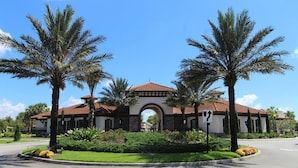 A building with a red-tiled roof, an arched entrance, and palm trees in the foreground. - ⛱ Solterra - 5★ Community - Disney Area - Games Room - Extended Pool and Deck ✈ (Davenport)