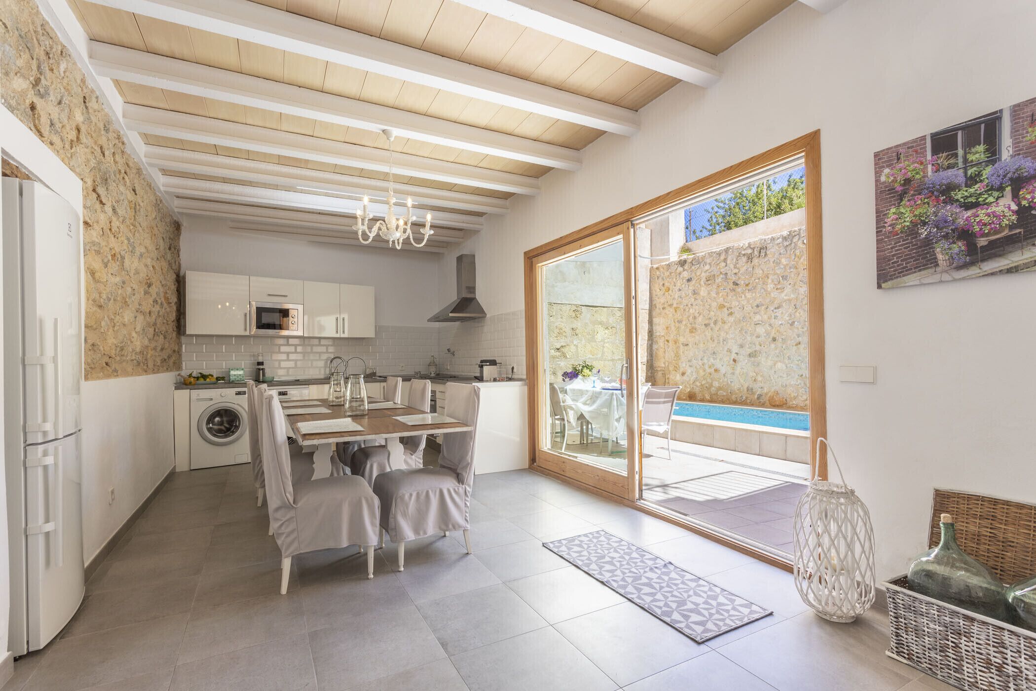 A modern kitchen with a dining area, a washing machine, and a view of a swimming pool.