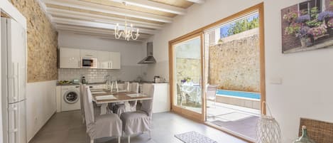 A modern kitchen with a dining area, a washing machine, and a view of a swimming pool.