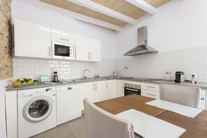A modern kitchen with white cabinetry, a built-in oven, and a washing machine.