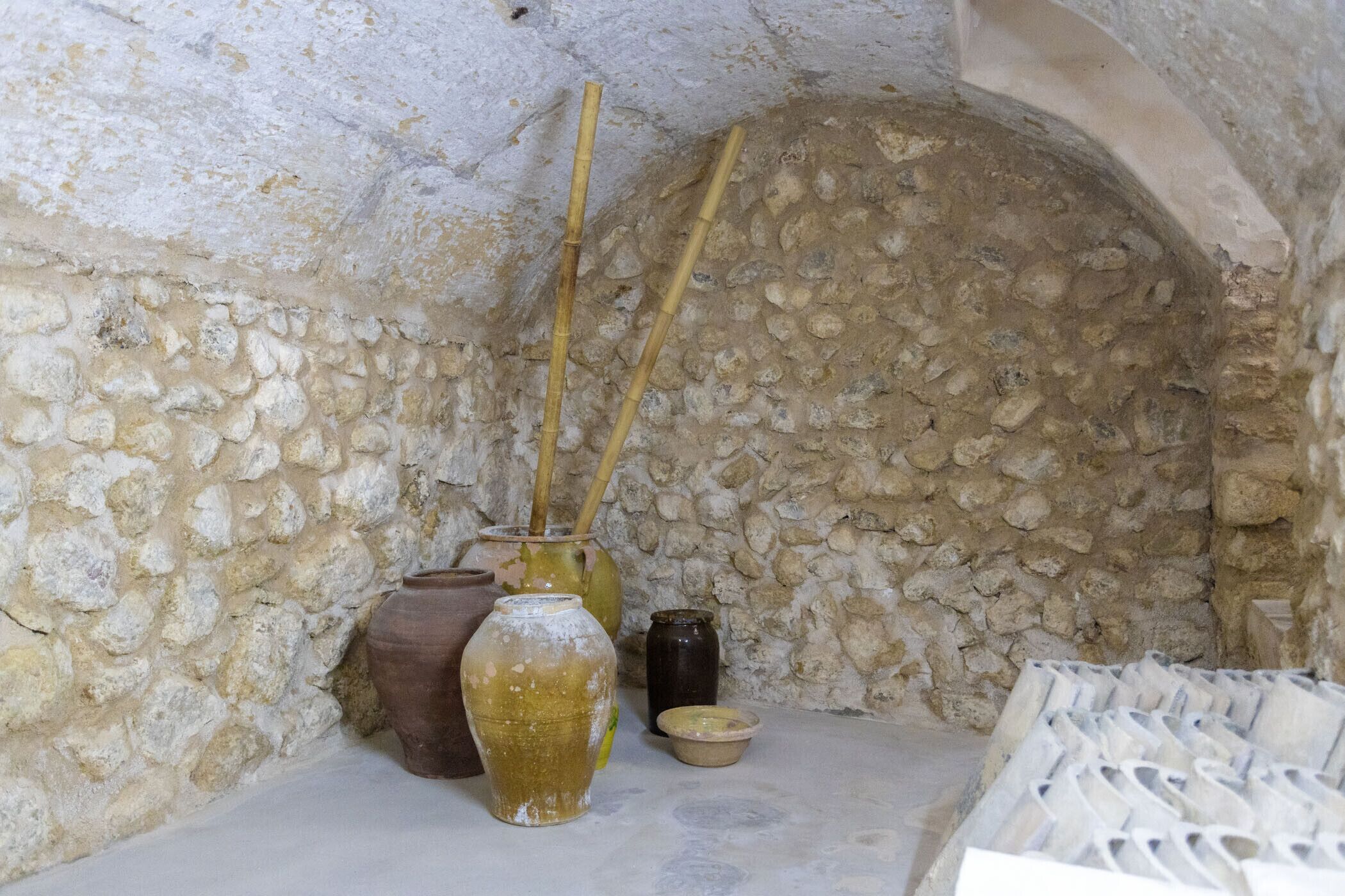 A stone wall with a small alcove containing pottery and a basket.