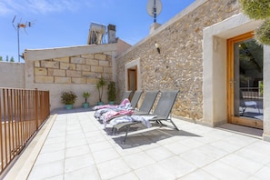 A stone building with a tiled patio, outdoor seating, and a door leading to a covered area. - Village house with pool, 3 bedrooms, 2 bathrooms, barbecue (Campanet)