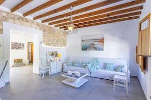 A spacious living area with a white sofa, a coffee table, and a painting on the wall.