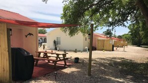 Un espace extérieur rustique agrémenté de structures en bois, d’une table de pique-nique et d’un barbecue.