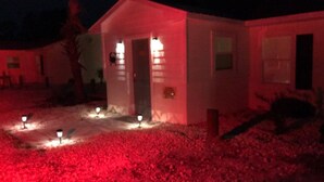 Un petit bâtiment d’un seul étage, doté d’une porte et de fenêtres, éclairé par des lumières rouges.