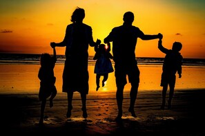 Eine Silhouette einer Familie vor einem Sonnenuntergang am Strand.