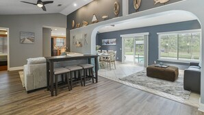 A spacious living area with a dining table, seating, and a ceiling fan. - HEATED Saltwater POOL, Harry Potter, BBQ, Lake, Fishing, Gazebo, Games & Firepit (St. Augustine)